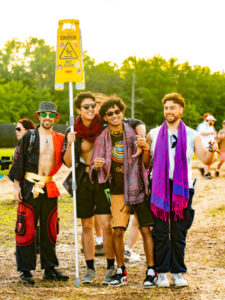 A group of festival goers with a caution wet floor sign.